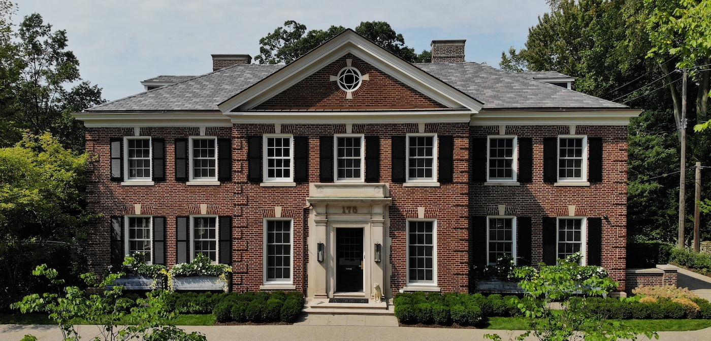 a house with bushes in front of a brick building