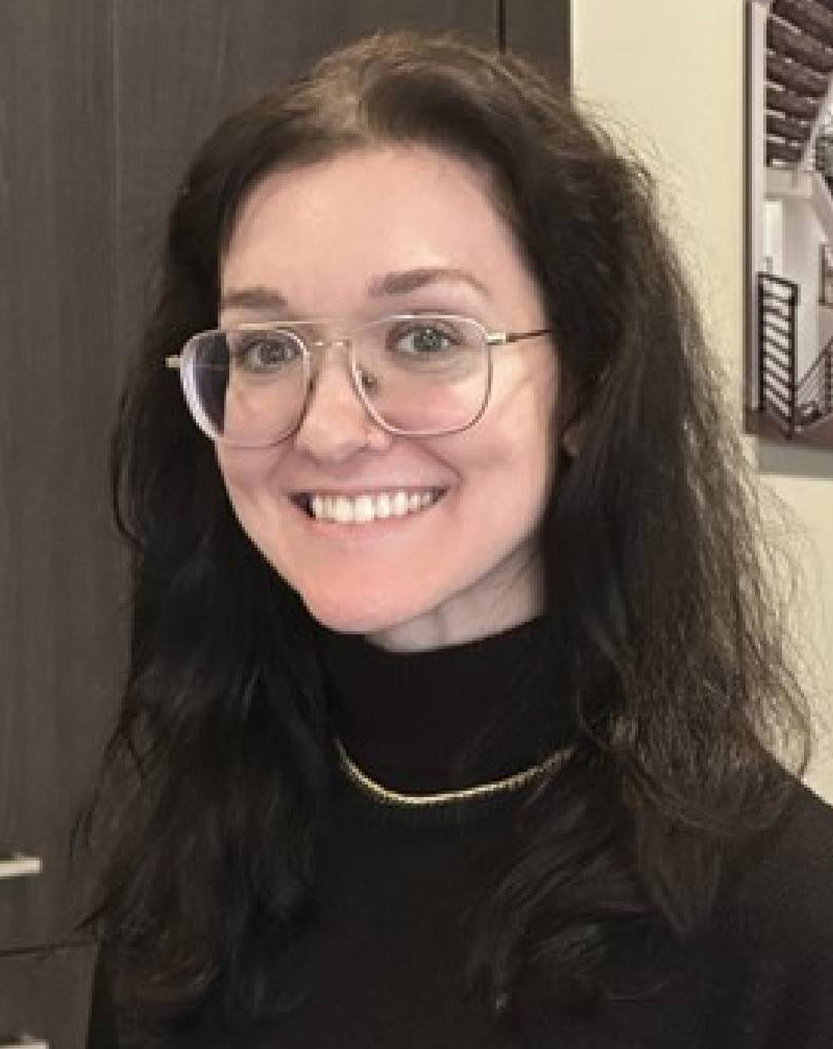 a woman wearing glasses and smiling at the camera