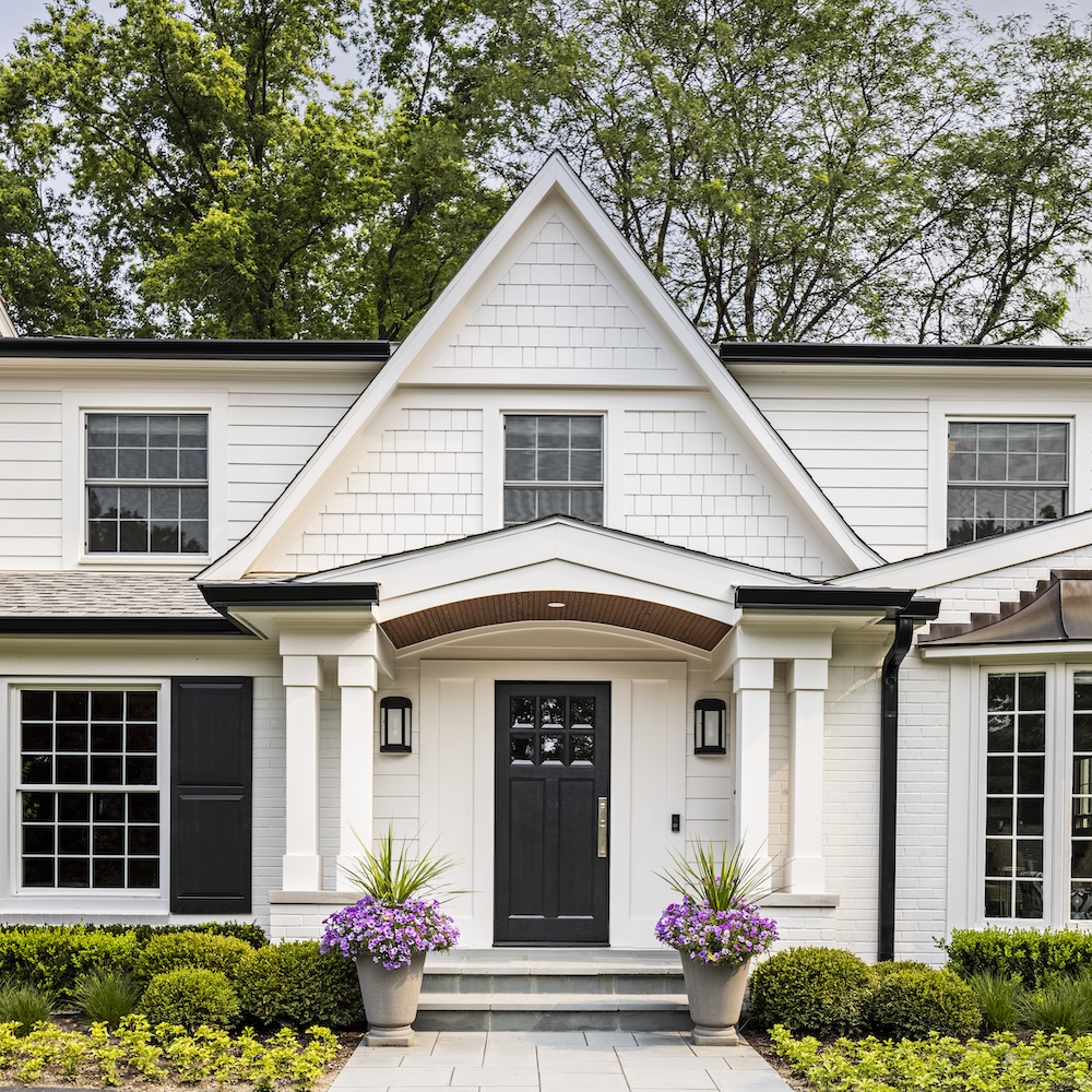 a close up of a flower garden in front of a house with American Gothic House in the background